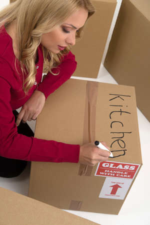 House moving. Top view of young woman writing on the cardboard boxの写真素材