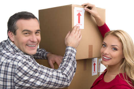 Happy couple. Cheerful middle-aged couple lying together between two cardboard box stacks and smilingの写真素材