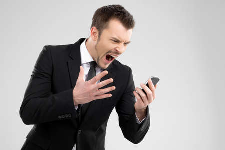 Angry businessman. Angry young man in formalwear shouting at mobile phone