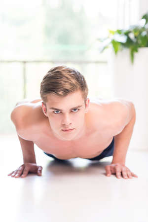 Exercising at home. Shirtless young man exercising at home