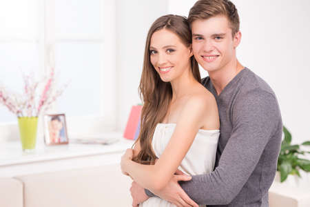 Loving couple. Beautiful young couple hugging and smiling at cameraの写真素材