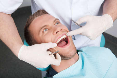 Patient at dentist office. Top view of man sitting at the chair in dental office and keeping mouth openの写真素材