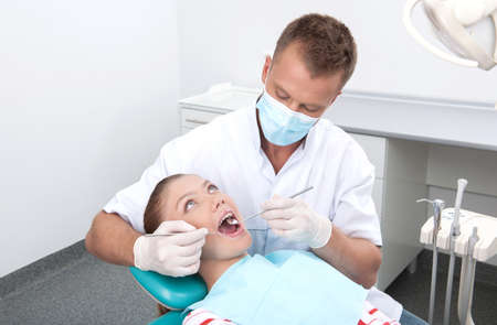 Patient at dentist office. Top view of teenage girl sitting at the chair at the dental office while doctor examining teethの写真素材