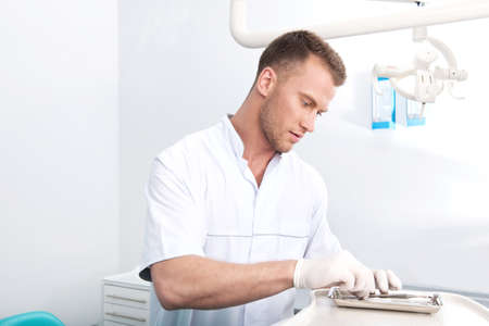 Confident dentist. Confident young dentist preparing dental equipmentの写真素材