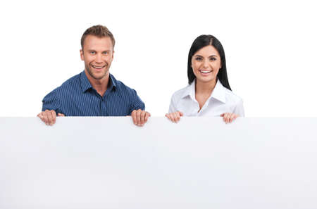 Happy business people. Cheerful young man and woman holding poster and smiling while isolated on whiteの写真素材