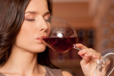 Woman drinking wine  Beautiful young woman drinking wine and keeping eyes closedの写真素材
