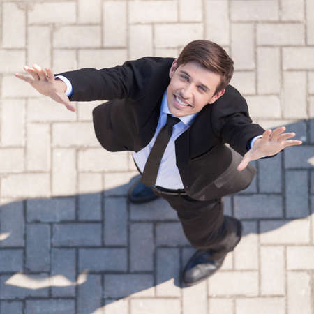 Happy businessman. Top view of cheerful young men in formalwear raising his hands up and smilingの写真素材