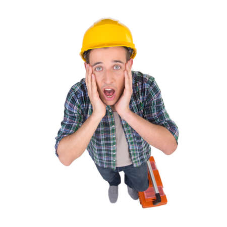 Handyman. Top view of frustrated craftsperson looking at camera and holding head in hands while isolated on whiteの写真素材