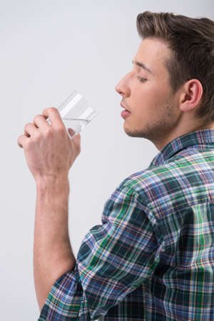 Man drinking water. Side view of handsome young men drinking water and keeping eyes closedの写真素材