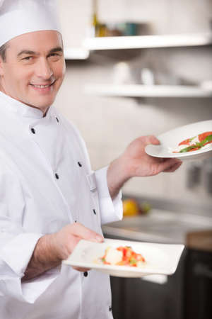Confident chef. Cheerful chef holding plates with food and smilingの写真素材