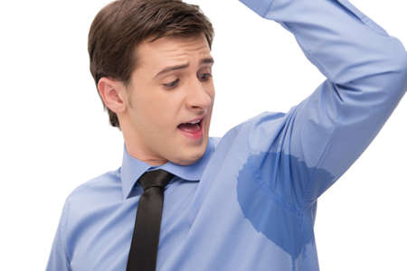 Young man is sweating a lot. Looking with surprice at spot on a shirt