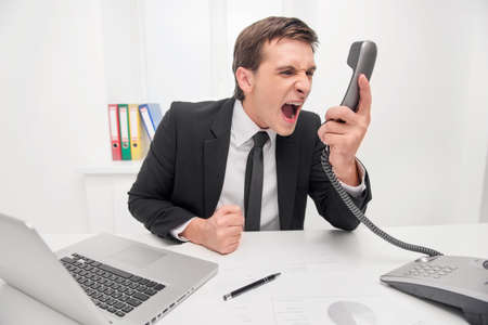 Young man is shouting by phoneの写真素材
