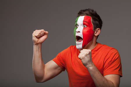 Footbal fan is rooting. With painted Italian flag on a faceの写真素材