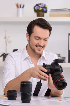 One man in white shirt is looking at photo in camera. Choosing photos