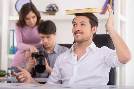 Man at foreground is making fun. Man and woman are choosing photos on the background
