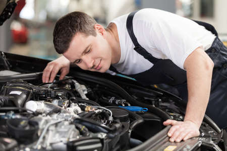 Confident auto mechanic. Confident mechanic listening to the car engine workingの写真素材