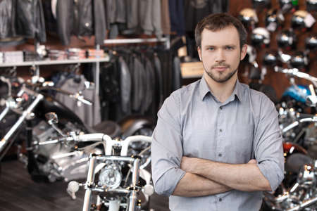 Confident sales executive. Confident young men standing in front of the motorcycles and holding his arms crossedの写真素材