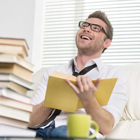 Cheerful smart men  Cheerful young men in glasses smiling away while holding a bookの写真素材