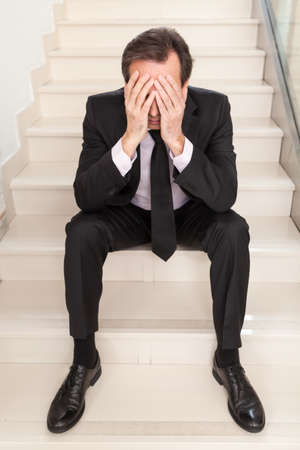 a busy businessman sits with his head in his heads during the fall.の写真素材