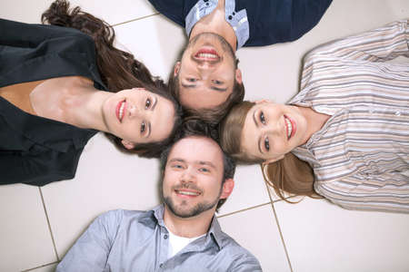 Top view of people laying together. Smiling holding heads togetherの写真素材