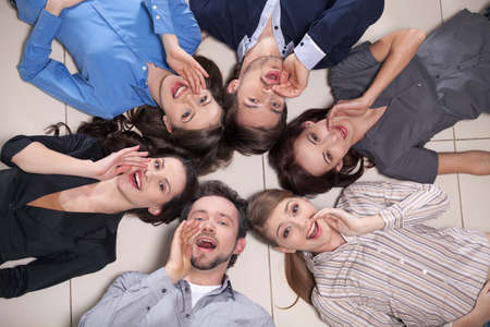 Top view of people laying in circle together. Everyone is telling something holding a  hand near mouthの写真素材