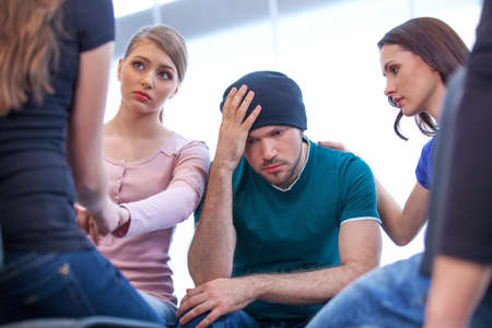 Group of people is looking for comfort. Young comforting a manの写真素材