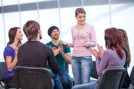 Young girl is shearing her thoughts in a group of people. All clappingの写真素材