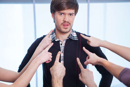 Image of fingers pointing at one man. Close up with window on backgroundの写真素材