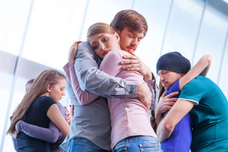 Three pair of people hugging each other. Girl with upset look on the foregroundの写真素材
