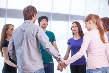 Group of people standing in circle. Holding hands, looking at each otherの写真素材