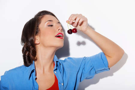 Woman with cherry. Beautiful young woman holding cherry while isolated on whiteの写真素材