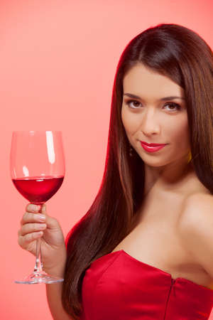 Woman with glass of wine  Beautiful young woman in red dress holding a glass with wine and looking at cameraの写真素材