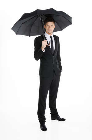 Serious businessman in a suit with umbrellaの写真素材