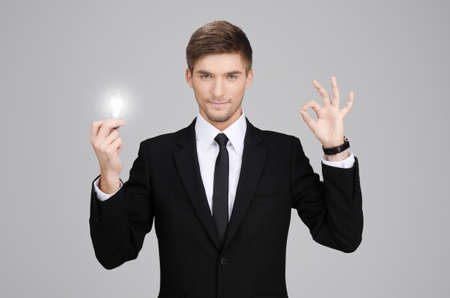 Businessman holding a light bulb and pointingの写真素材