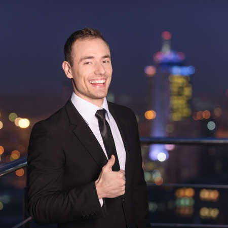 Satisfied businessman on background night cityの写真素材