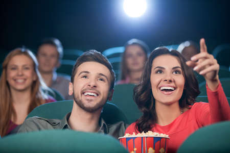 Happy couple at the cinema. Cheerful young couple watching movie at the cinemaの写真素材