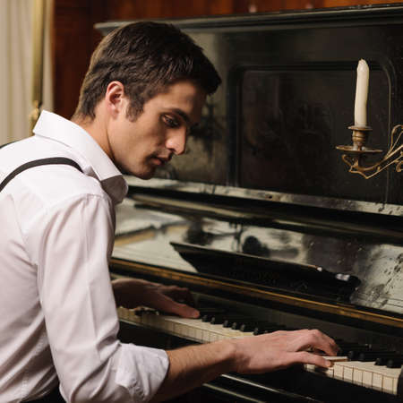Making music. Profile of a handsome young men playing pianoの写真素材