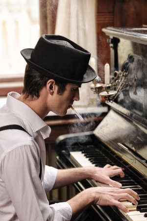 Heï¿½ got his own technique. Profile of handsome young men playing piano and smoking cigaretteの写真素材