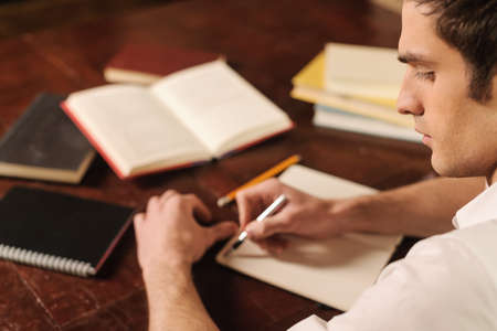 It is so important to start with the right words. Handsome young author sitting at the table and going to start writing his storyの写真素材