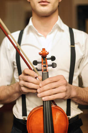 Men holding the violin. Young musician standing with the violin in his handの写真素材
