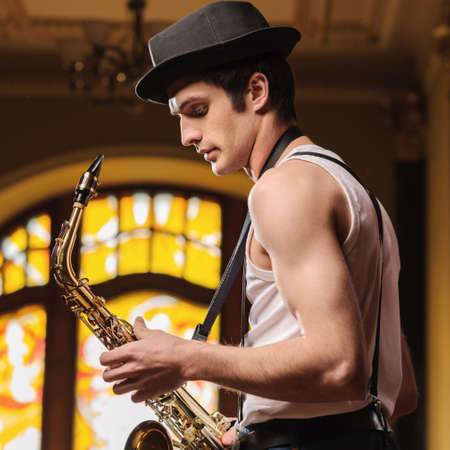 Ready for improvising. Handsome young jazzmen standing with saxophone in his handsの写真素材