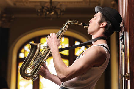 Playing funky music. Handsome young jazzmen playing sax with his eyes closedの写真素材