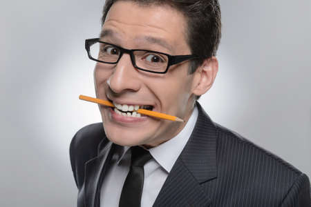Unpleased businessman. Portrait of businessman holding a pencil in his mouth and looking at cameraの写真素材