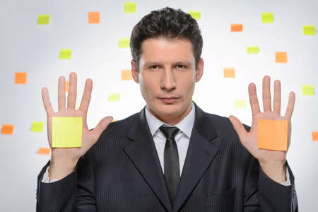 Choose the task. Portrait of confident businessman holding his hands outstretched with the adhesive notes on themの写真素材