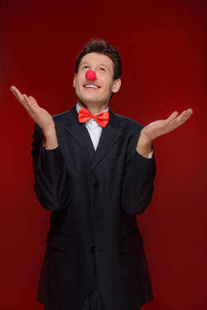 Man juggling. Cheerful man with a clown nose juggling while standing isolated on redの写真素材