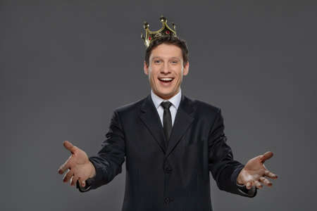 Happy to be a business leader  Cheerful businessman with outstretched hands standing against gray backgroundの写真素材
