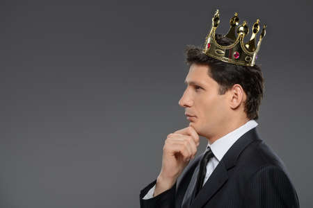 Thoughtful business king  Side view of confident businessman thinking with his hand on chinの写真素材