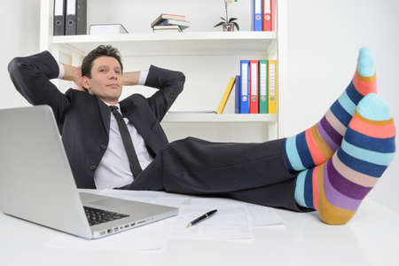 Businessman in funky socks  Confident businessman holding his legs in funny socks on the deskの写真素材