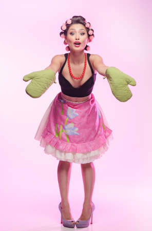 What would you like to have on dinner? Sexy young housewife wearing gloves and standing with her hands outstretchedの写真素材