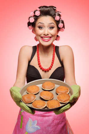 Iï¿½e cooked this for you! Happy young housewife standing with a pan full of cakesの写真素材